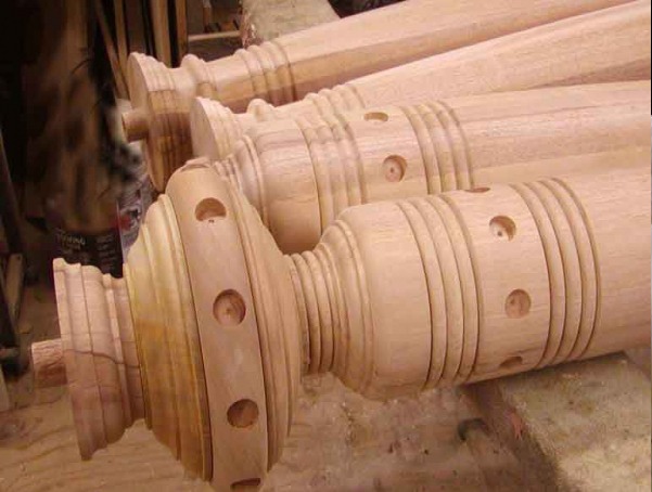 Large wooden column featuring an elliptical finial with circular cutouts and ring detail.